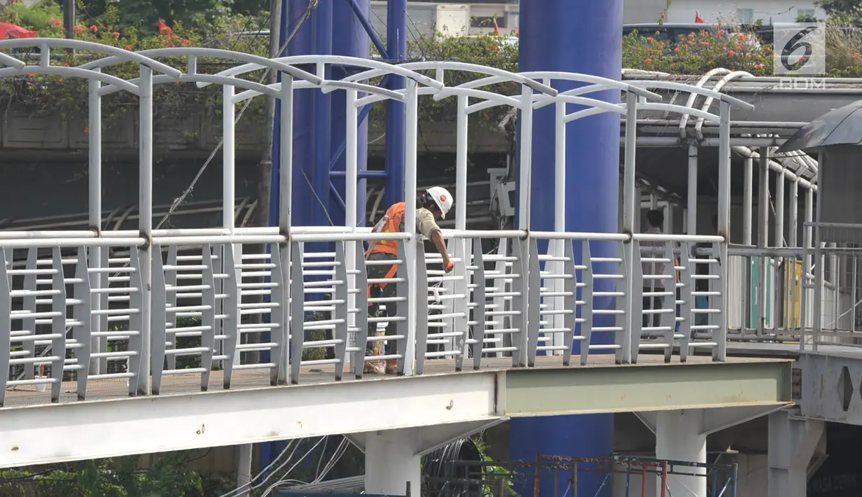 Seorang pekerja mengecat pagar jembatan penyeberangan orang (JPO) di Halte Kuningan Timur, Jakarta, Selasa (9/1). Sebelumnya, JPO yang ada dibongkar karena pembangunan LRT. (Liputan6.com/Immanuel Antonius)