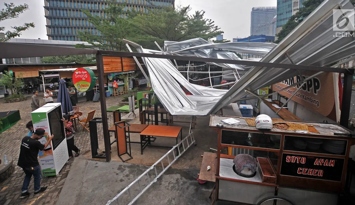 Pedagang mengevakuasi barang-barang kios Rasuna Garden Food Street usai roboh akibat angin kencang, Kuningan, Jakarta, Senin (10/12). Hujan disertai angin kencang menerbangkan sekaligus merobohkan atap dan sebagian bangunan. (Merdeka.com/Iqbal Nugroho)