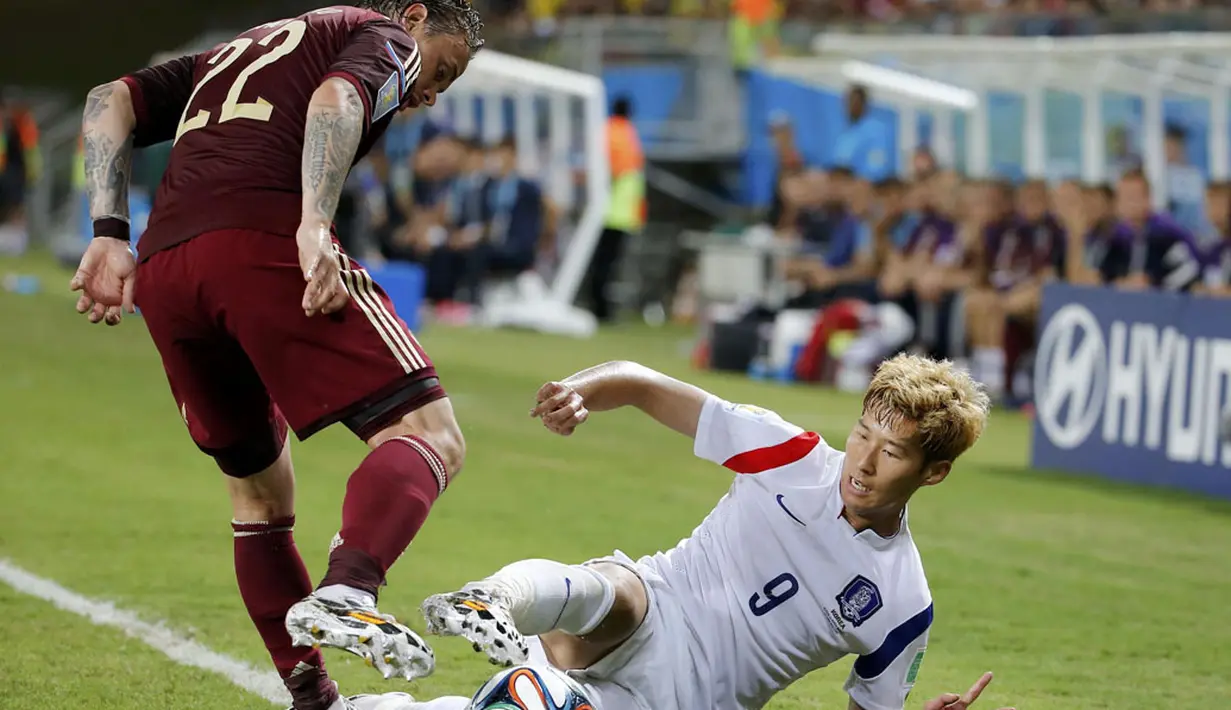 Pemain belakang Rusia, Andrey Eshchenko (kiri), berusaha merebut bola dari Heung Min Son (Korea Selatan) saat berlaga di babak penyisihan Piala Dunia 2014 Grup H, Pantanal Arena, Cuiaba, Brasil, (18/6/2014). (REUTERS/Eric Gaillard)   