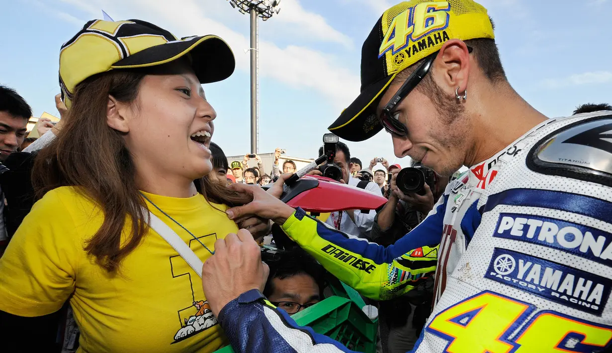 Pebalap MotoGP, Valentino Rossi, memberikan tanda tangan kepada fans wanita saat GP Jepang di Sirkuit Motegi, Jepang, Jumat (1/10/2010). (AFP/Toru Yamanaka)