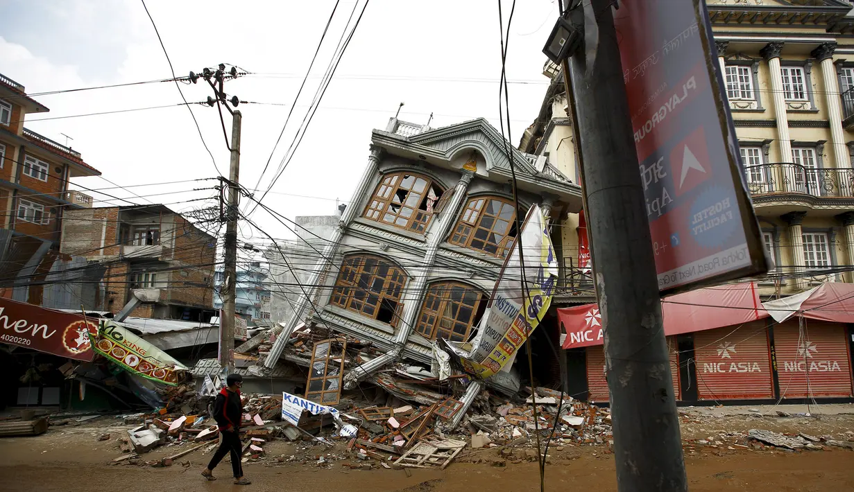 Foto yang diambil pada 1 Mei 2015 menunjukkan warga berjalan di dekat rumah yang runtuh setelah gempa 7,8 SR di Kathmandu. Setahun yang lalu, Nepal mengalami gempa terburuk dalam sejarah selama 80 tahun bencana di kawasan itu. (REUTERS/Navesh Chitrakar)