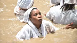 Seorang wanita pengikut Voodoo Haiti mandi di kolam suci selama upacara voodoo di Souvenance, Haiti (4/1). Voodoo dibawa ke Haiti oleh para budak dari Afrika Barat. (AFP/Hector Retamal)