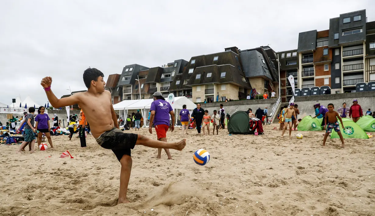 Seorang anak bermain sepak bola di pantai Cabourg, barat laut Prancis (18/8/2021). Acara ini sebagai bagian dari kampanye "Lupa Liburan" yang diselenggarakan oleh LSM Prancis Secours Populaire untuk anak-anak yang keluarganya tidak mampu pergi berlibur. (AFP/Sameer Al-Doumy)