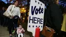 Warga mengajak bayinya saat akan memberikan suara pemilihan presiden AS di Alexandria, Virginia, AS, Selasa (8/11). Warga AS akan menentukan presiden mereka antara Hillary Clinton dan Donald Trump. (AFP Photo/Alex Wong)