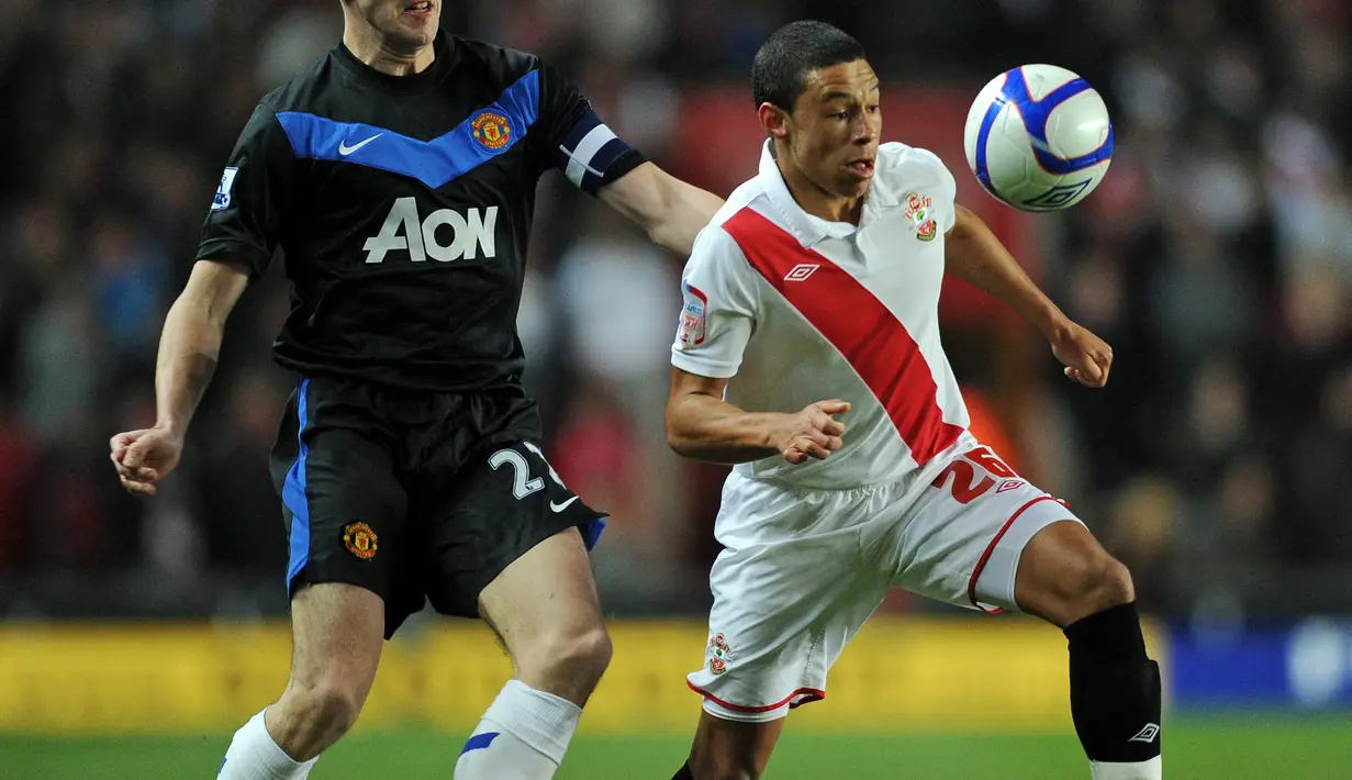 Pemain Southampton, Alex Oxlade-Chamberlain (kanan) berebut dengan pemain Manchester United, John O'Shea pada laga Piala FA di St Mary's Stadium, Southampton, Inggris, 29 Januari 2011. Jersey milik Southampton pada musim 2010/2011 terlihat sangat sederhana. Jersey tersebut didominasi warna putih dengan aksen strip miring berwarna merah. (AFP/Adrian Dennis)