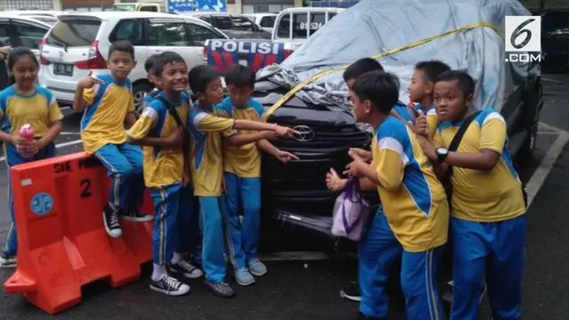Sekumpulan anak SD berfoto bersama mobil yang mengangkut Setya Novanto hingga mengalami kecelakaan