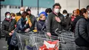 Orang-orang mengenakan masker antre di luar sebuah supermarket di Casalpusterlengo, Minggu (23/2/2020). Mereka memborong perlengkapan dan bahan-bahan kebutuhan pokok karena tak mau keluar rumah menyusul dua warga Italia yang meninggal karena Virus Corona COVID-19. (Claudio Furlan/Lapresse via AP)