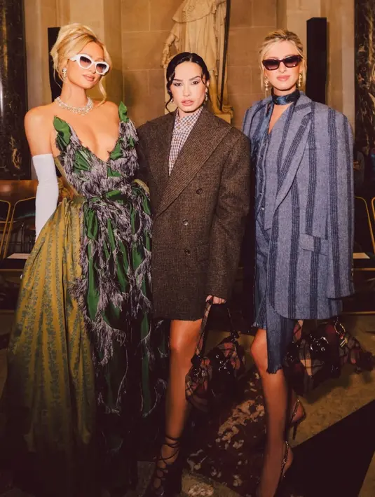 <p>Demi Lovato tampil mengenakan jas oversize sebagai outer dipadukan inner kemeja kotak-kotak dengan gaya pants less. Ia pun membawa handbag motif kotak-kotak sambil mengenakan heels hitam bertali. [@parishilton]</p>