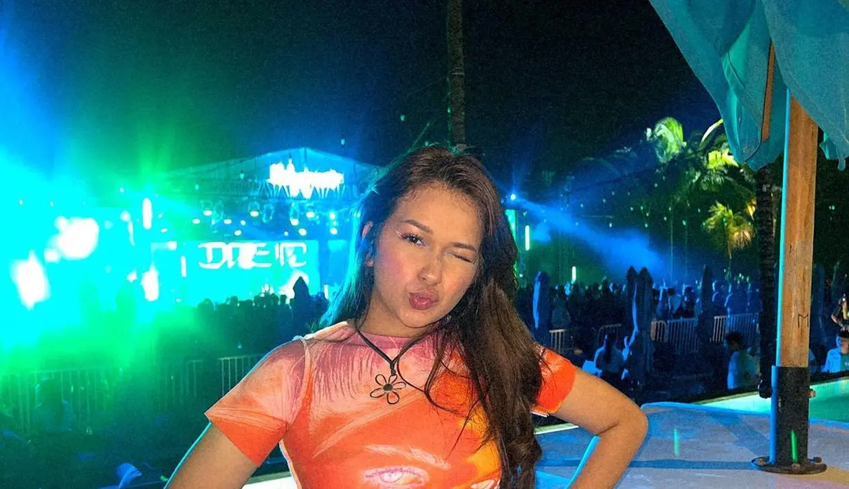 Nonton konser dengan tampilan yang chic ala Rebecca Klopper. Ia mengenakan atasan dengan ujung asimetris berwarna tie-dye oranye, dipadu dengan short pants denim. Foto: Instagram.