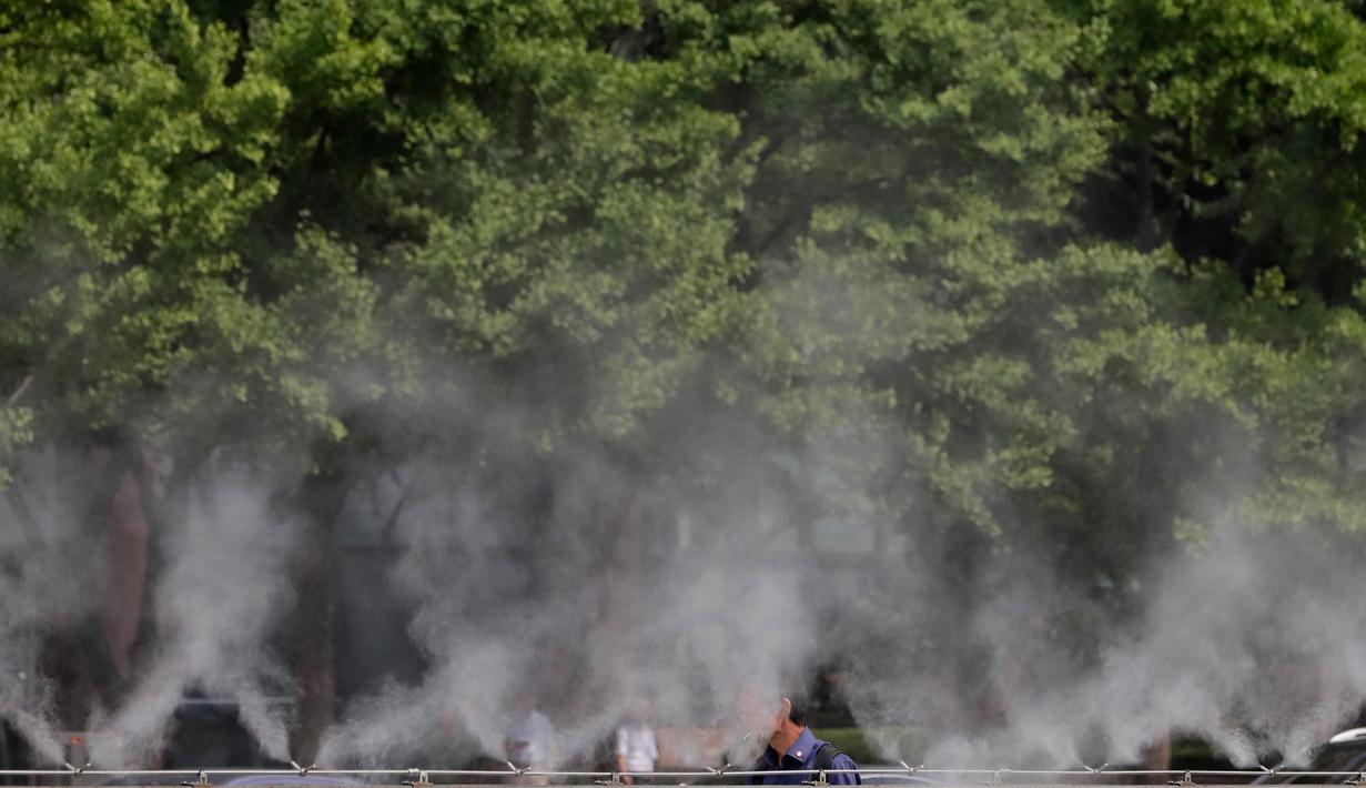 Pengunjung berjalan melalui kabut air untuk mendinginkan diri di Lapangan Gwanghwamun, Seoul, Korea Selatan, Senin (23/7). (AP Photo/Lee Jin-man)