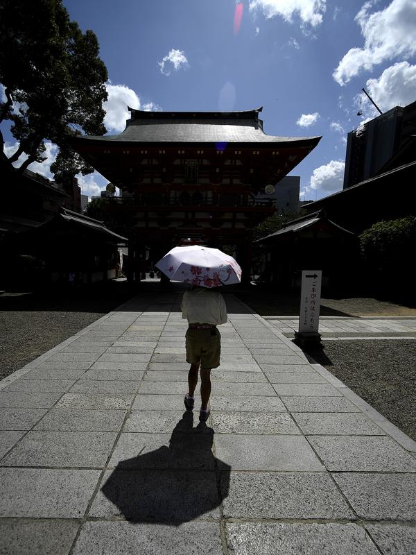 Pengunjung mengenakan payung saat mengunjungi Kuil Ikuta terlihat di pusat Kobe (5/10/2019). Kuil, dengan sejarah lebih dari 1.800 tahun ini dikatakan sebagai salah satu kuil tertua di Jepang. (AFP Photo/Monteforte)