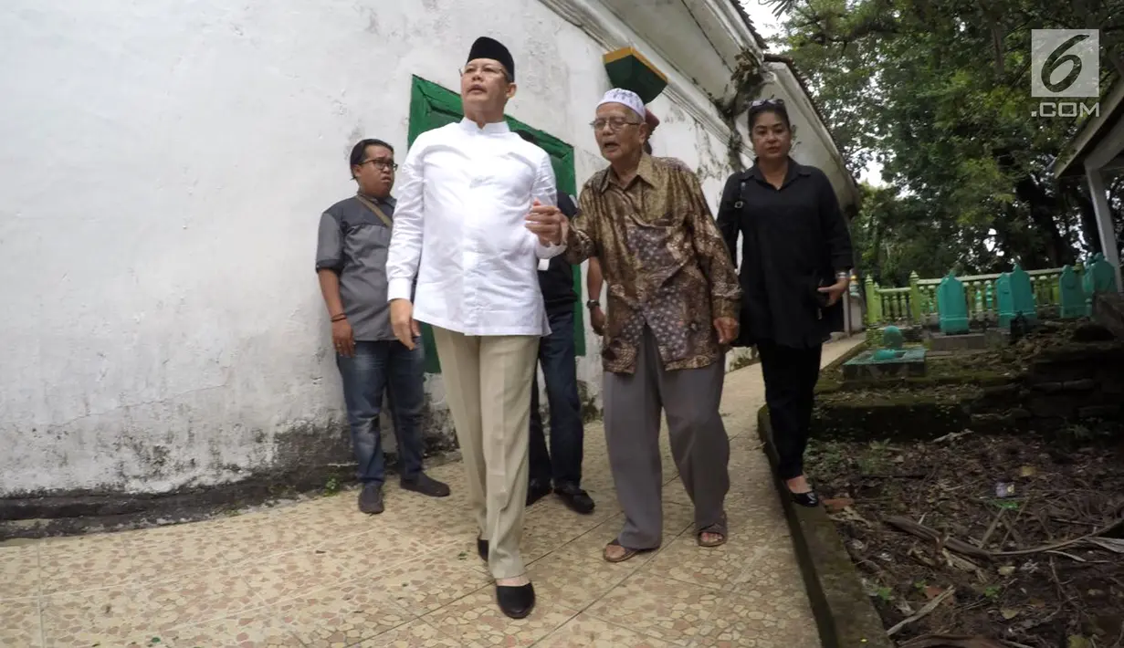 Saifudin Aswari menggandeng seorang kakek saat ziarah ke makam Sultan Mahmud Badaruddin di Palembang, Sumsel, Jumat (26/1). Saifudin Aswari dan M Irwansyah didukung oleh Partai Gerindra dan PKS. (Liputan6.com/Aswari)