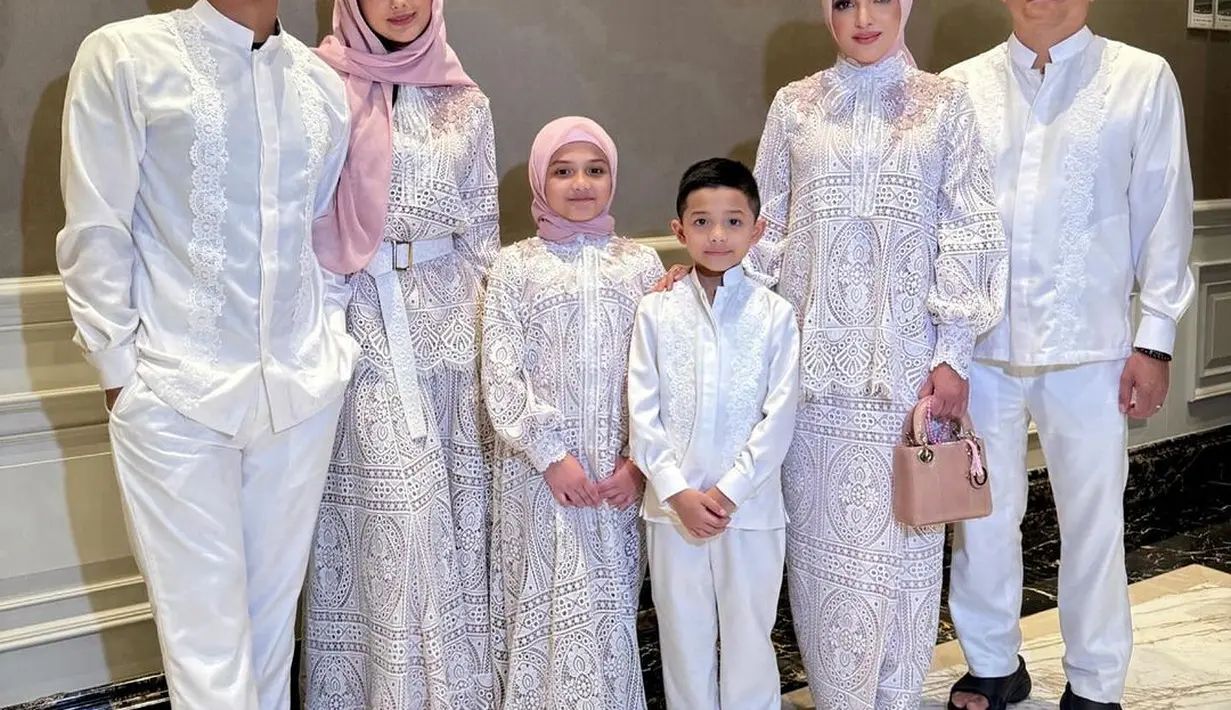 Ashanty pilih kenakan busana setelan blouse puffy sleeve dan rok panjang  brukat warna putih. Busana ini memiliki aksen pita tulle sebagai pemanis [@ashanty_ash]