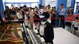Pengunjung mengambil gambar robot "Teotronico" yang memainkan piano dalam acara Konferensi Robot Dunia 2017 di Beijing, 23 Agustus 2017. Selain memainkan piano, robot rancangan Matteo Suzzi ini juga dapat menyanyikan lagu-lagu populer. (WANG Zhao/AFP)