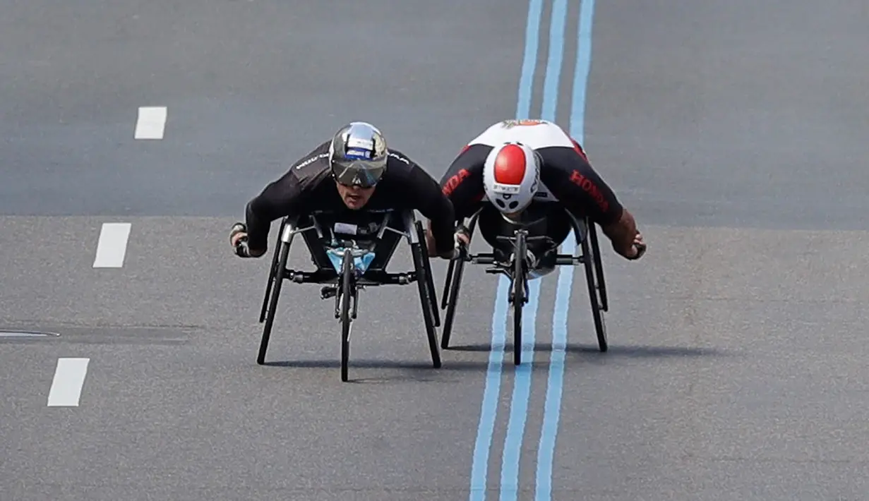 Atlet asal Swiss, Marcel Hug (kiri) dan atlet asal Afrika Selatan, Ernst Van Dyk bersaing dalam kejuaraan balap kursi roda kategori pria pada ajang Boston Marathon ke-121 di Boston, Senin (17/4). (AP Photo/Charles Krupa)