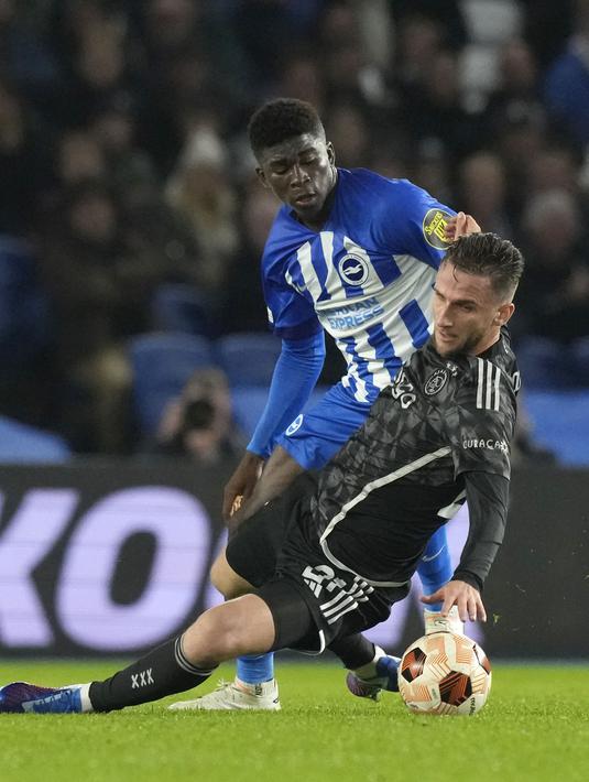 Pemain Brighton, Carlos Baleba (kiri) berusaha melewati penjagaan pemain Ajax Amsterdam, Branco van den Boomen pada laga Grup B Liga Europa 2023/2024 di American Express Community Stadium, Brighton, Inggris, Jumat (27/10/2023) dini hari WIB. (AP Photo/Frank Augstein)