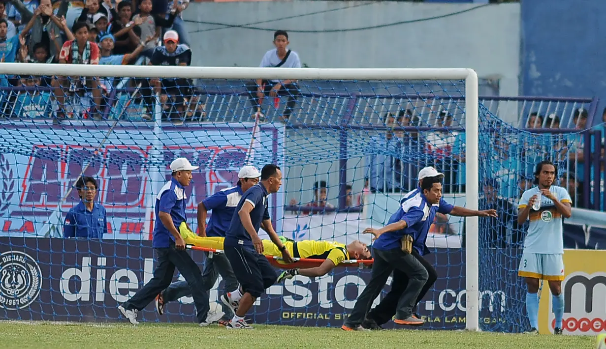 Kiper Persela Lamongan Choirul Huda dibawa oleh tim medis usai mengalami benturan dengan rekan setim, Ramon Rodrigues saat pertandingan Liga 1 di stadion Surajaya, Lamongan (15/10). (AFP Photo/Juni Kriswanto)