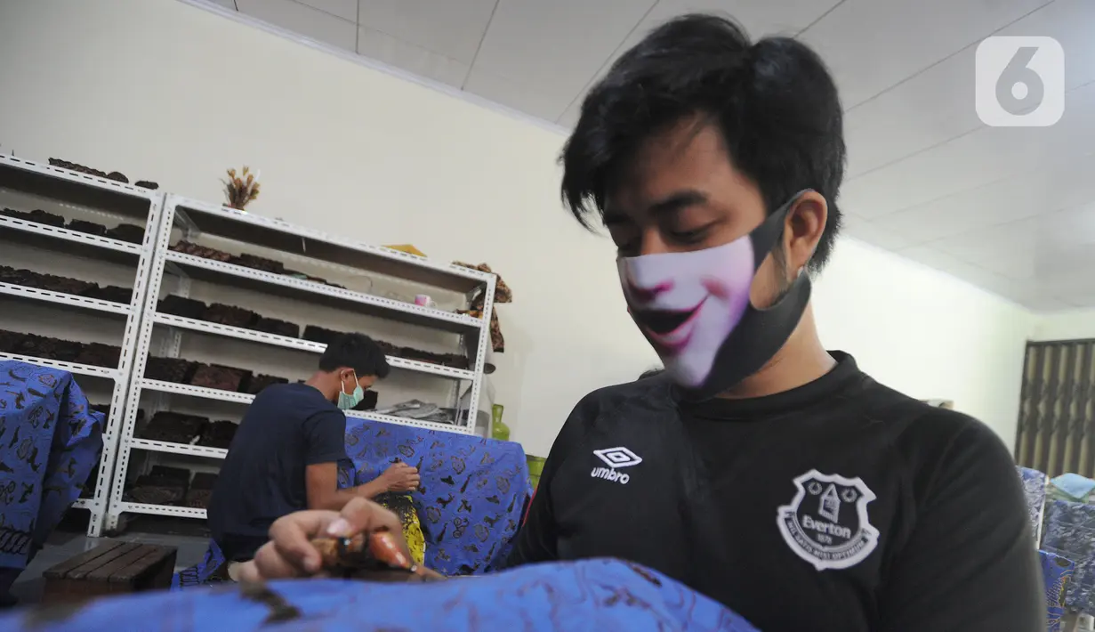 Perajin menyelesaikan proses pembuatan batik di  Batik Tradisiku, Bogor, Jawa Barat, Kamis (6/8/2020). Perajin batik mitra binaan Pertamina ini berinovasi dengan membuat motif dan warna baru untuk mengatasi anjloknya penjualan batik sebagai dampak ekonomi wabah corona. (merdeka.com/Arie Basuki)