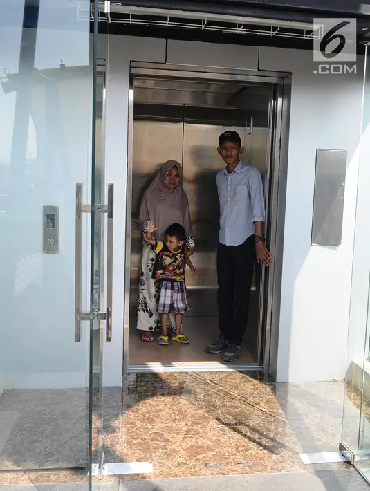 Petugas membantu warga menaiki lift jembatan penyeberangan orang (JPO) Sumarno, Jakarta, Kamis (10/1). Lift JPO Sumarno bisa digunakan setiap Senin sampai Jumat. (Liputan6.com/Herman Zakharia)