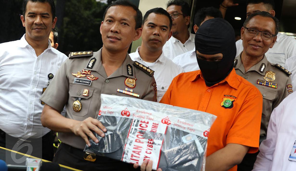 Kabid Humas Polda Metro Jaya Kombes Awi Setiyono memperlihatkan barang bukti beserta tersangka kasus videotron porno di Prapanca, Kebayoran Baru, berinisal SAR, saat rilis kasus videotron di Polda Metro Jaya, Rabu (5/10). (Liputan6.com/Immanuel Antonius)