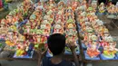 Seorang anak melukis patung Dewa Ganesha yang dipajang untuk dijual di kios pinggir jalan di Hyderabad, India, Kamis (9/9/2021). Patung dewa Hindu berkepala gajah tersebut banyak dijual jelang Festival Ganesh Chaturthi. (NOAH SEELAM/AFP)
