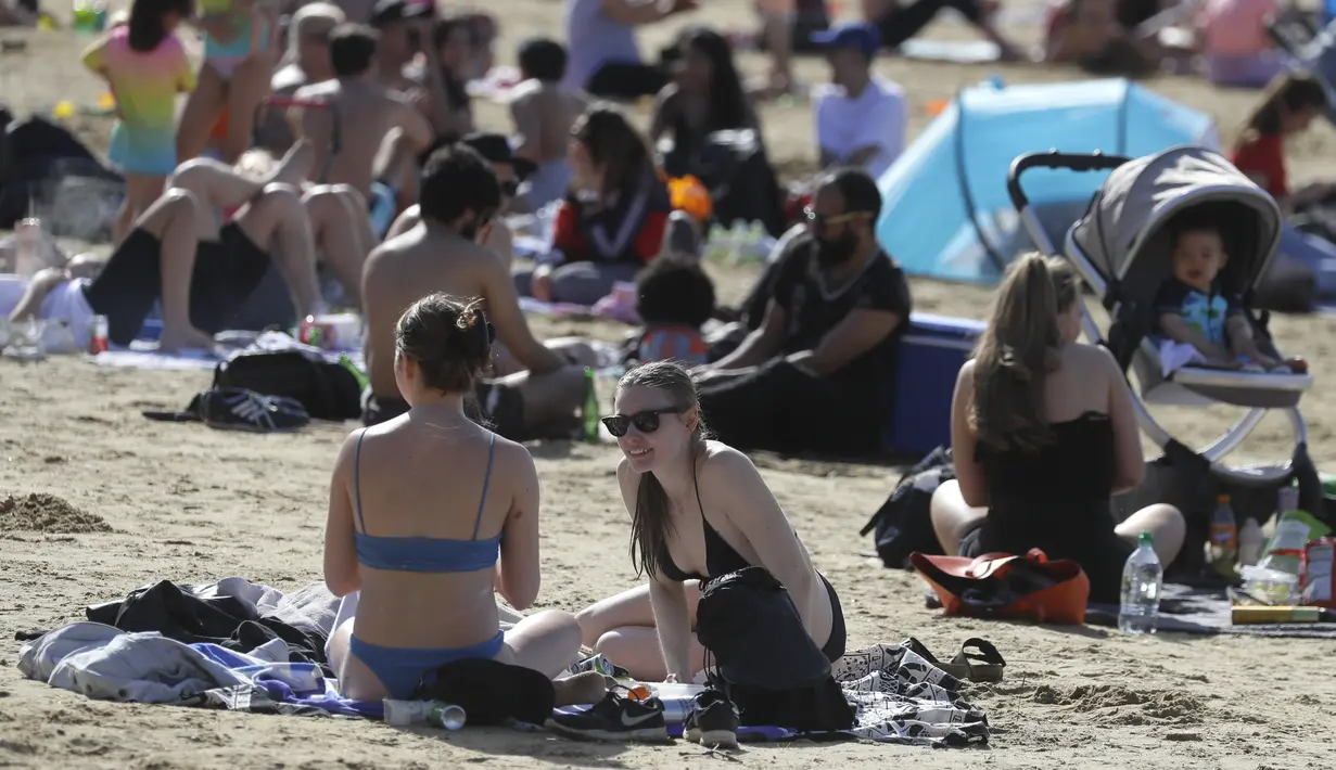 Orang-orang menikmati cuaca hangat di Ruislip Lido di London, Selasa (30/3/2021).  Suhu di beberapa bagian Inggris diperkirakan akan lebih hangat secara signifikan minggu ini karena keluarga dan teman berkumpul kembali dan kegiatan olahraga luar ruangan diizinkan untuk dilanjutkan di Inggris. (AP Ph