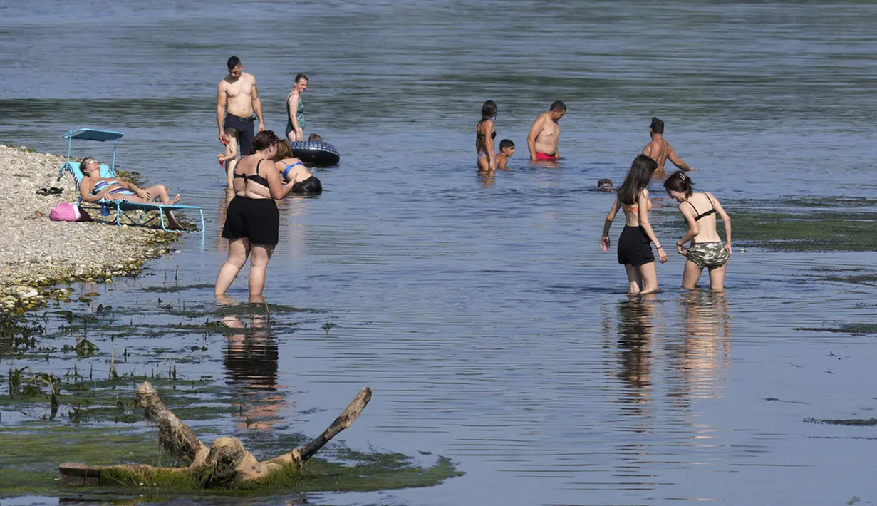 <p>Orang-orang mendinginkan diri di tepi Sungai Ticino, Ponte delle Barche (jembatan perahu), Bereguardo, dekat Milan, Italia, 11 Juli 2023. Gelombang panas yang hebat telah mencapai Italia, membawa suhu mendekati 40 derajat Celcius di banyak kota di seluruh negeri. (AP Photo/Antonio Calanni)</p>