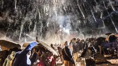 Pengunjung melindungi diri dari percikan kembang api balon udara panas dalam Festival Tazaungdaing di Taunggyi, Myanmar (12/11). Festival ini merupakan salah satu perayaan paling indah dan berbahaya di Asia.(AFP/Ye Aung Kamis)