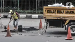 Pekerja meratakan aspal saat perbaikan jalan berlubang di Jalan DI Panjaitan, Cawang, Jakarta, Senin (25/1/2021). Perbaikan jalan rusak dan berlubang akibat sering tergenang banjir di kawasan tersebut dilakukan untuk mengantisipasi terjadinya kecelakaan pengendara. (merdeka.com/Iqbal S Nugroho)