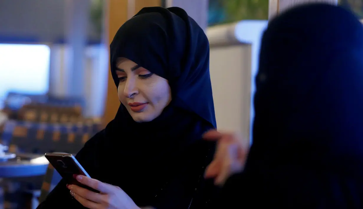 Seorang wanita berhijab memainkan ponselnya saat berada di sebuah kafe di Riyadh, Arab Saudi (6/10). (REUTERS/Faisal Al Nasser)