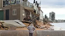 Seorang warga melihat bangunan yang rusak akibat badai yang melanda Pantai Utara Sydney (6/6/2016). Tiga orang dikabarkan tewas akibat cuaca buruk tersebut. (AFP Photo/William West)