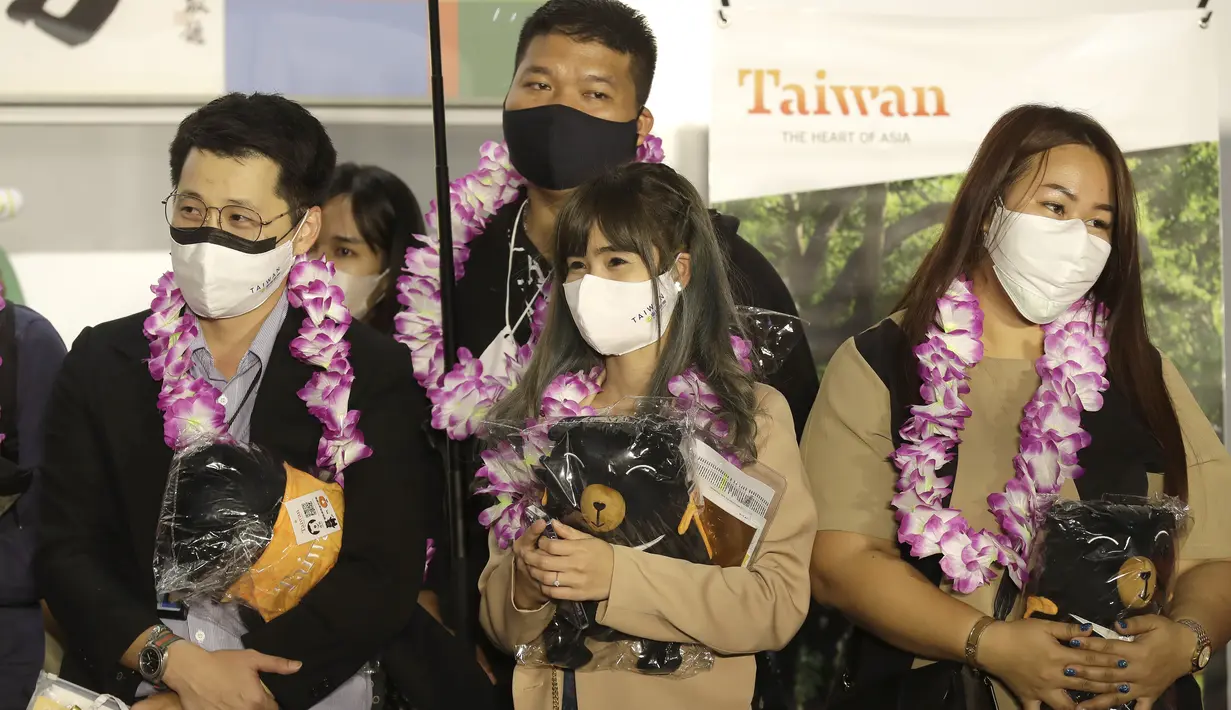 Rombongan pertama wisatawan asing memegang suvenir setelah tiba di Bandara Internasional Taoyuan di Taoyuan, Taiwan Utara, Kamis (13/10/2022). Taiwan mengumumkan mengakhiri karantina wajib COVID-19 bagi orang yang datang dari luar negeri mulai 13 Oktober. (AP Photo/Chiang Ying-ying)