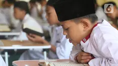 Santri yang masih berusia belasan tahun membaca Al Quran bersama-sama (tadarus) dalam rangka mengkhatamkan Qur'an dengan menerapkan jaga jarak pada Masjid Daarul Qu'ran  Pesantren Al Kautsar, Cibinong, Bogor, Jawa Barat, Minggu (10/04/2022). (merdeka.com/Arie Basuki)