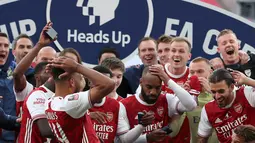 Striker Arsenal, Pierre-Emerick Aubameyang (tengah) menjatuhkan trofi saat merayakan gelar juara Piala FA usai mengalahkan Chelsea pada pertandingan final Piala FA di stadion Wembley, Minggu (2/8/2020).  Aubameyang terlihat kaget sambil memegang kepalanya saat trofi terjatuh. (Adam Davy/Pool via AP)