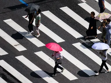 Pejalan kaki menggunakan payung saat menyeberangi jalan di Seoul pada tanggal 14 Agustus 2024. (Anthony WALLACE/AFP)