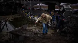 Seorang wanita berlari saat dia melarikan diri bersama keluarganya melintasi jembatan yang hancur di pinggiran Kyiv, Ukraina, 2 Maret 2022. Perang Rusia-Ukraina berkobar sejak 24 Februari 2022 tanpa tahu kapan akan berakhir. (AP Photo/Emilio Morenatti, File)