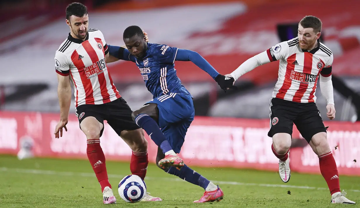 Penyerang Arsenal, Nicolas Pepe berusaha melewati dua pemain Sheffield United, Enda Stevens dan John Fleck pada pertandingan Liga Inggris di stadion Bramall Lane, Inggris, Senin (12/4/2021). emenangan ini membuat Arsenal berada di peringkat kesembilan klasemen. (Laurence Griffiths/Pool via AP)