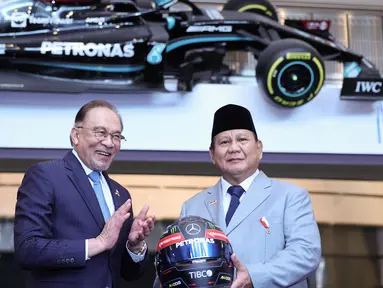 Presiden Republik Indonesia, Prabowo Subianto (kanan) menerima helm Mercedes AMG Petronas F1 Team sebagai kenang-kenangan dari Perdana Menteri Malaysia, Anwar Ibrahim dalam sebuah pertemuan di Kuala Lumpur pada tanggal 27 Januari 2025. (HASNOOR HUSSAIN/POOL/AFP)