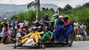 Para peserta menuruni bukit menggunakan kendaraan buatan mereka sendiri dalam festival kendaraan luncur dengan nama Car Festival di Medellin, Kolombia, 17 November 2019. Car Festival ke-30 ini menggunakan gerobak buatan yang dibuat mirip seperti mobil. (JOAQUIN SARMIENTO/AFP)