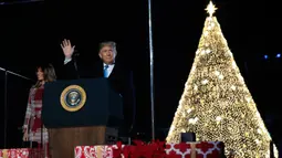 Presiden AS, Donald Trump dan ibu negara Melania Trump menghadiri upacara penerangan pohon cemara, yang menjadi Pohon Natal Nasional di taman sebelah selatan Gedung Putih, Kamis (5/12/2019). Pohon cemara setinggi 30 kaki tersebut dihiasi 50.000 lampu dan 450 bintang. (AP/Manuel Balce Ceneta)