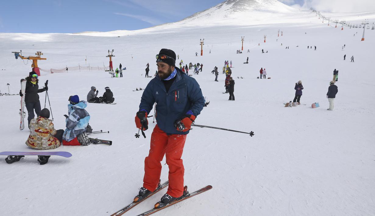 Seorang pemain ski menuruni lereng di resor ski Tochal di luar ibu kota Teheran, Iran (1/1/2022). Di tengah polusi udara dan kesengsaraan ekonomi, penduduk Teheran menemukan kenyamanan di resor ski di utara Teheran di pegunungan Alborz. (AP Photo/Vahid Salemi)