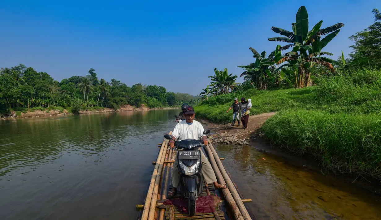 Warga bersama sepeda motornya menyeberangi Sungai Cisadane menggunakan rakit bambu di kawasan Ciseeng, Kabupaten Bogor, Jawa Barat, Kamis (11/6/2026). (merdeka.com/Arie Basuki)