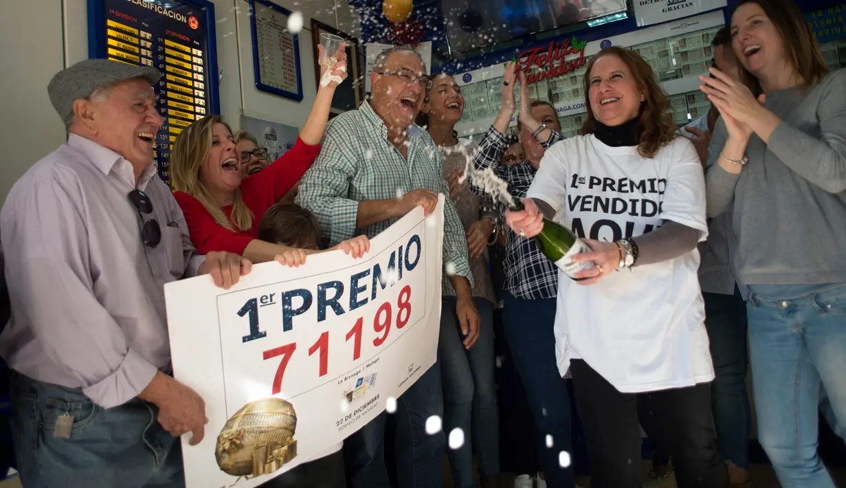 Penjual tiket undian dan pemenang merayakan kemenangan di sebuah toko lotre di Malaga, Spanyol (22/12). Sebanyak 22 orang karyawan di panti wreda itu menang hadiah utama lotre Natal tahunan Spanyol. (AFP Photo/Jorge Guerrero)