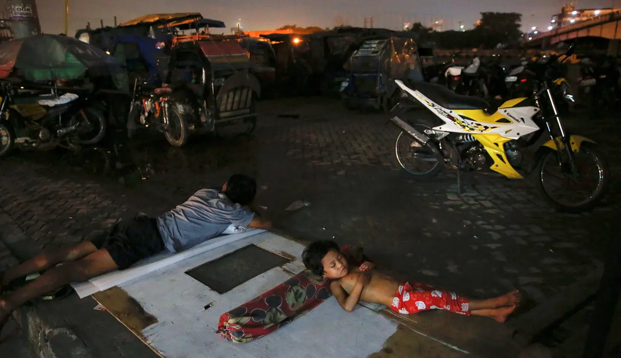 Warga dan anaknya tidur di udara terbuka di kawasan Tondo, Manila, Selasa (18/10). Banyak warga Filipina memilih tidur di jalan dan meninggalkan rumah mereka karena khawatir menjadi sasaran terkait operasi anti-narkoba Duterte. (REUTERS/Damir Sagolj)