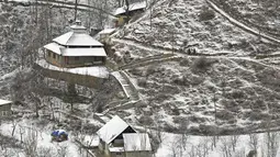 Rumah-rumah yang tertutup salju digambarkan setelah hujan salju di pinggiran Srinagar, Kashmir, India, pada 29 Desember 2020. Hujan salju memutihkan kota utama di Kashmir tersebut. (Photo by Tauseef MUSTAFA / AFP)