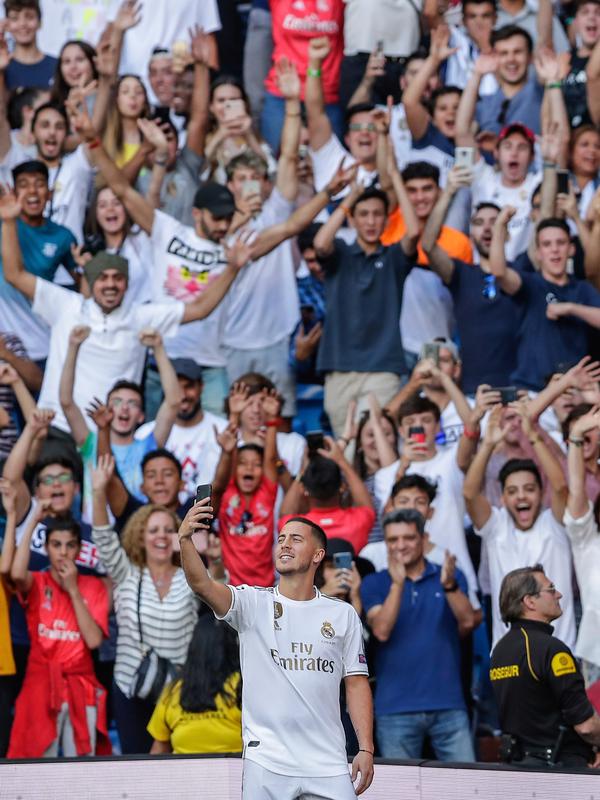 Pemain baru Real Madrid, Eden Hazard berselfie dengan fans saat diperkenalkan di stadion Santiago Bernabeu di Madrid, Spanyol (13/6/2019). Eden Hazard dibeli dari Chelsea senilai 100 juta euro. (AP Photo/Manu Fernandez)