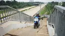 Pengendara sepeda motor melintasi JPO yang melintang di atas Tol Cijago Seksi II di Depok, Jawa Barat, Rabu (15/5). Meskipun berbahaya, namun curamnya akses JPO tidak menjadi penghalang bagi sebagian pemotor untuk menyeberang agar dapat memersingkat waktu tempuh. (Liputan6.com/immanuel Antonius)