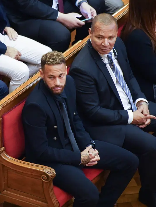Mantan pemain Barcelona, Neymar (kiri) yang sekarang bermain untuk Paris Saint-Germain melambaikan tangan saat tiba di ruang pengadilan di Barcelona, Spanyol, Senin (17/10/2022). Neymar kembali ke Spanyol untuk menghadiri persidangan atas tuduhan penipuan terkait transfer dari Santos ke Barcelona pada 2013 lalu. (AP Photo/Joan Mateu Parra)