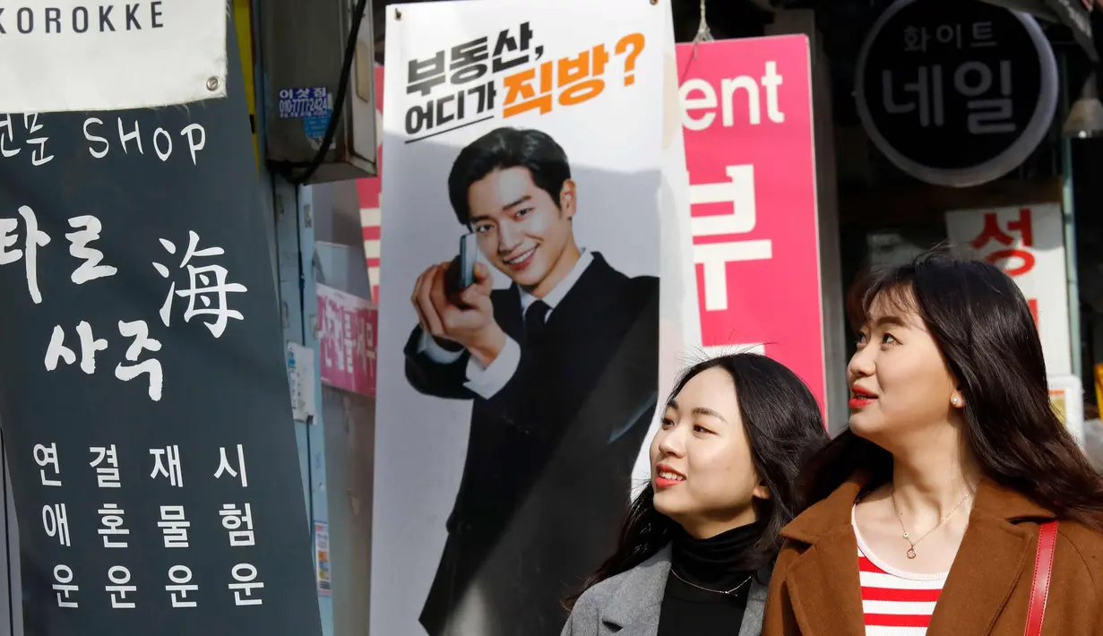 Dua wanita berbincang sambil berjalan di sepanjang jalan di Seoul, Korea Selatan (19/2). (AFP Photo/David Gannon)