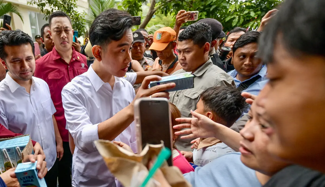 Gibran terlihat membagikan susu kemasan ke sejumlah anak anak yang mengerumuninya. (BAY ISMOYO/AFP)